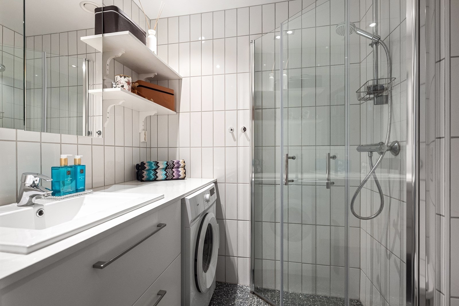 Badet har en moderne utførelse med flislagt gulv, lyse overflater og behagelig gulvvarme. Gulvvarmen på badet er elektrisk. Himlingen er nedsenket med downlights som gir god belysning og et stilrent uttrykk. Galleribilde