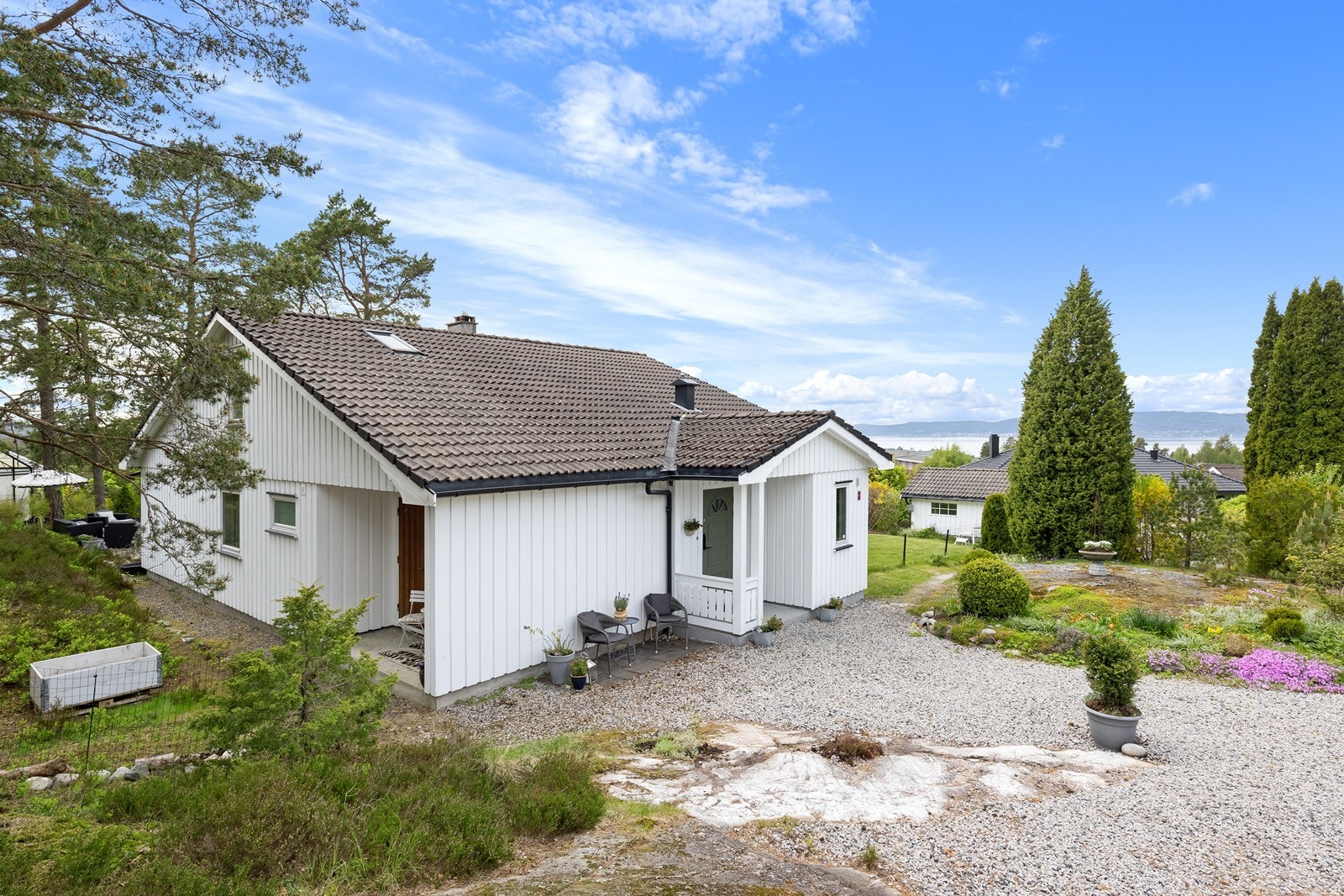 Enebolig over to plan med frittstående garasje. Gårdsplassen er gruset med plass til parkering. Galleribilde