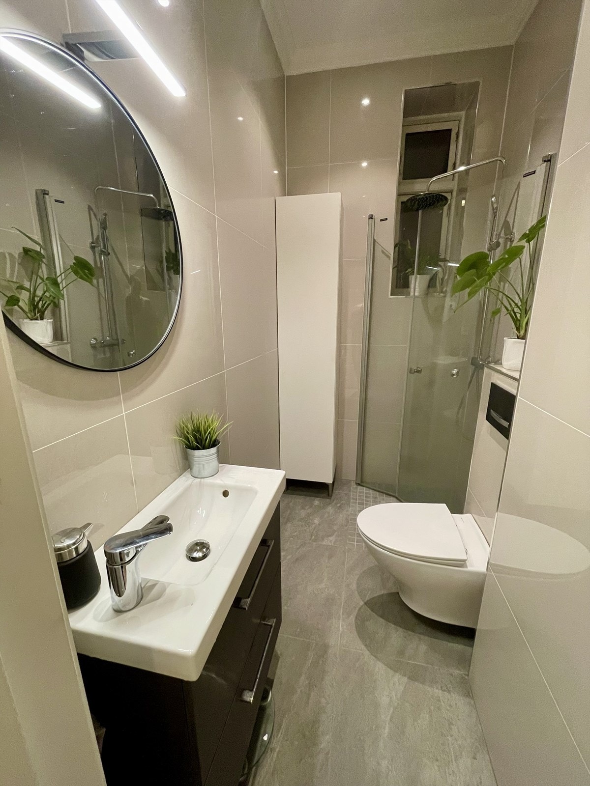 Bad fra 2020 med benkeskap med glatte fronter og speil over servant, dusjhjørne og veggfestet klosett Galleribilde