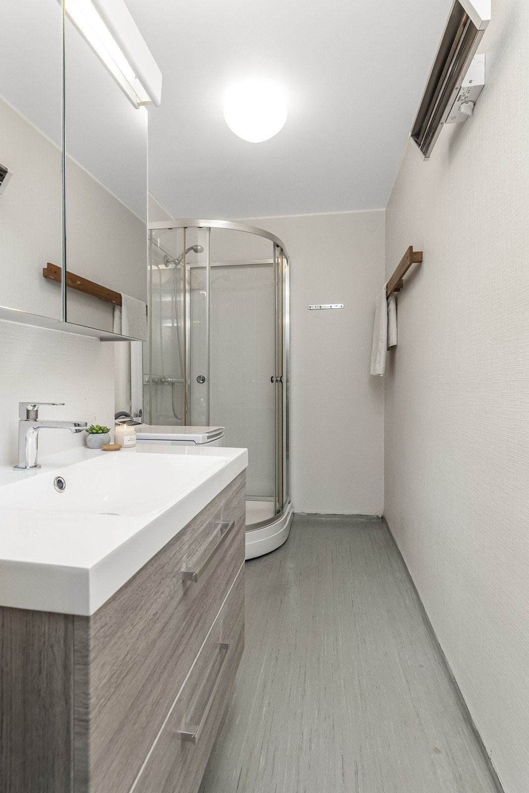 Badet er av eldre dato, men har fått flere oppgraderinger de siste årene. Baderominnredning ble fornyet 2025 med moderne servantskap med skuffer og heldekkende servant. Over innredning er det speilskap for oppbevaring. Galleribilde