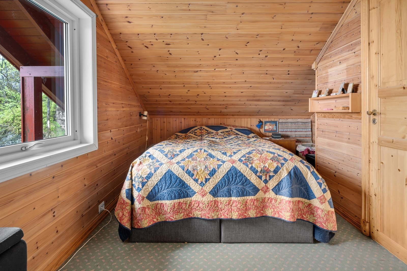 Det ene av to soverom på loftet, med trepanel på vegger og tak. Galleribilde