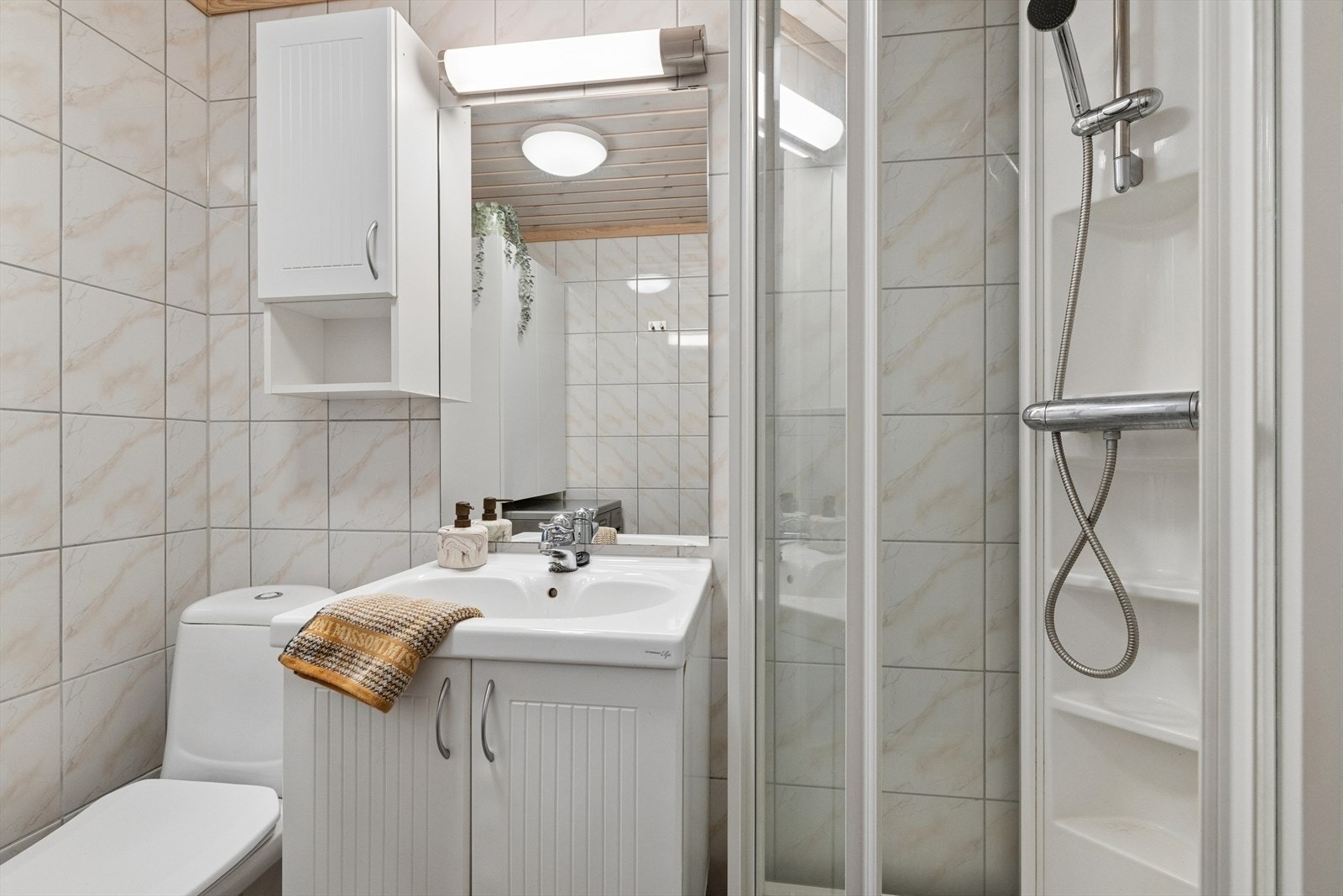 Badet er ellers praktisk utstyrt med toalett, dusjkabinett og baderomsinnredning med god lagringsplass og nedfelt servant. I tillegg har man opplegg for vaskemaskin med skap over for ekstra lagring. Galleribilde