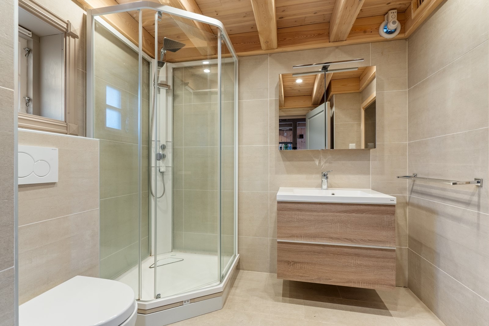 Badet i eldhuset har flislagte overflater, dusjkabinett og vegghengt toalett. Galleribilde