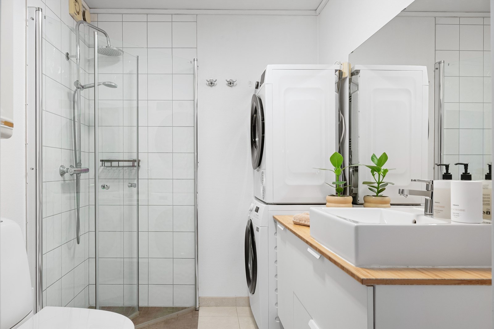 Badet fremstår som lyst og har flisbelagt gulv med varmekabler.
Veggene i dusjhjørnet er flisbelagt. Det er også opplegg til vaskemaskin. Galleribilde