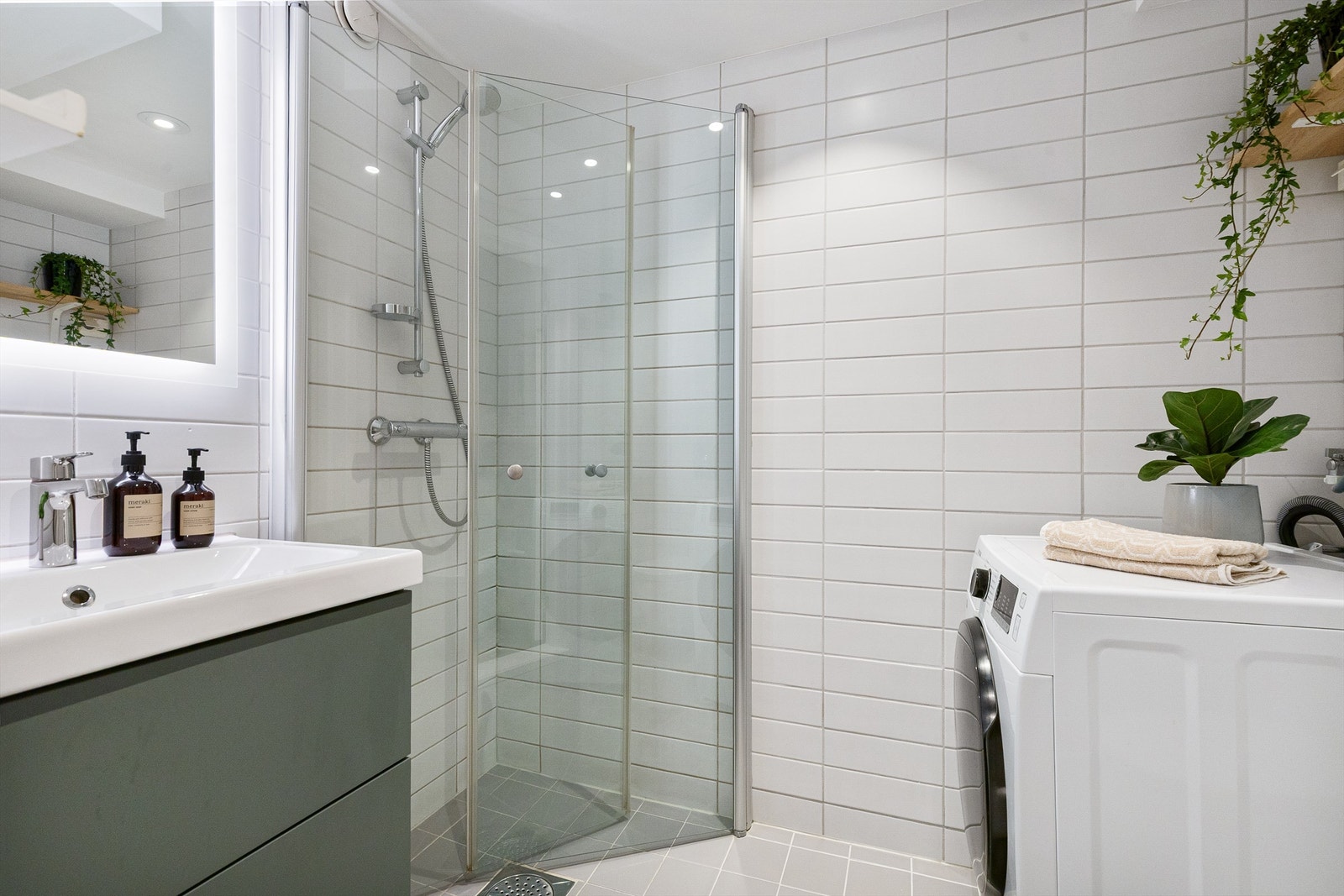 Badet har dusjnisje med glassdører og opplegg for vaskemaskin. Galleribilde
