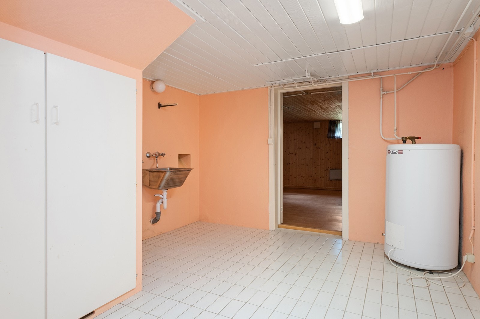 Vaskerom i kjeller med fliser på gulv, utslagskum og opplegg for vaskemaskin. Galleribilde