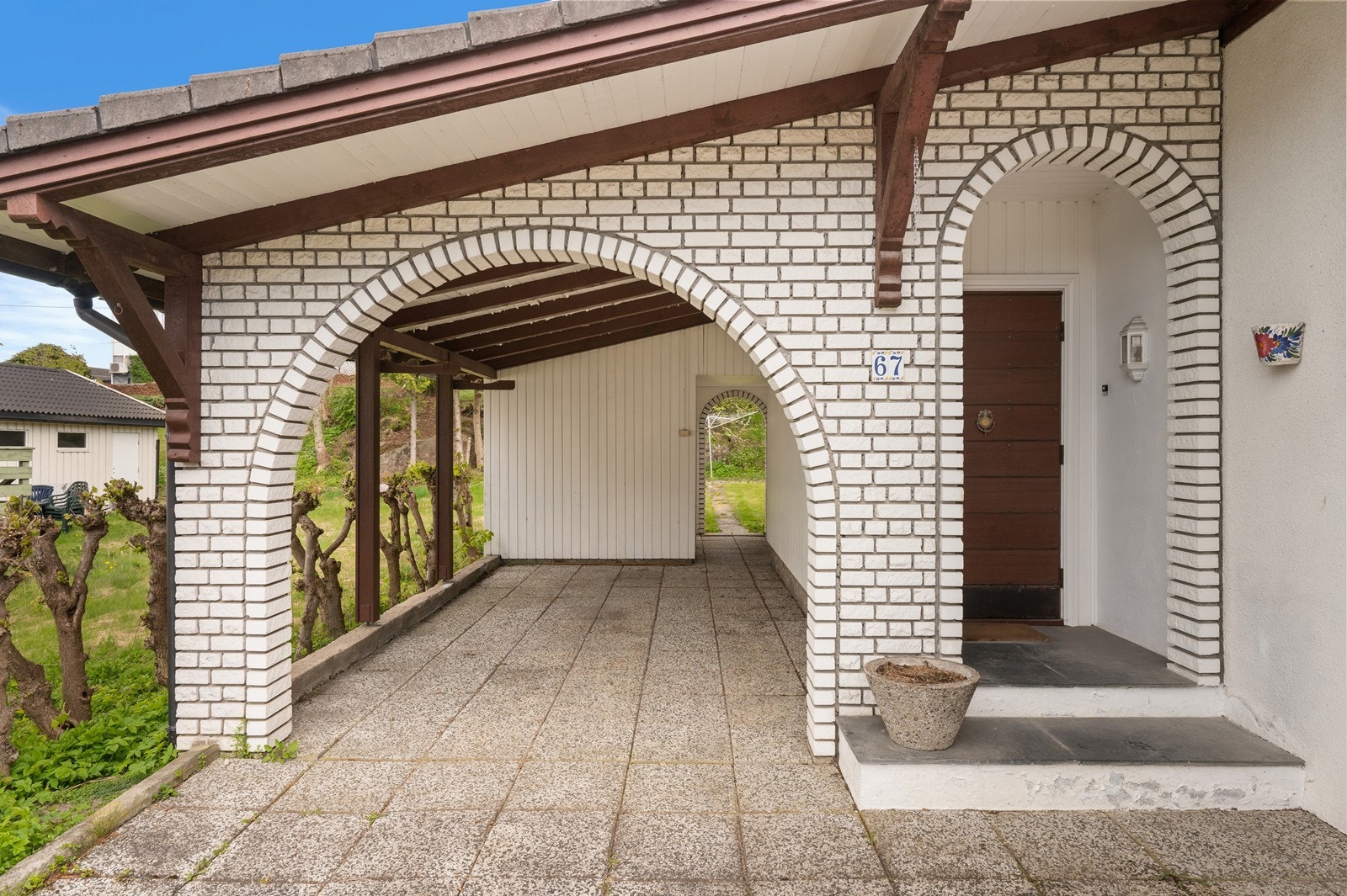 Carporten er oppført med betongringmur og trepilarer. Galleribilde