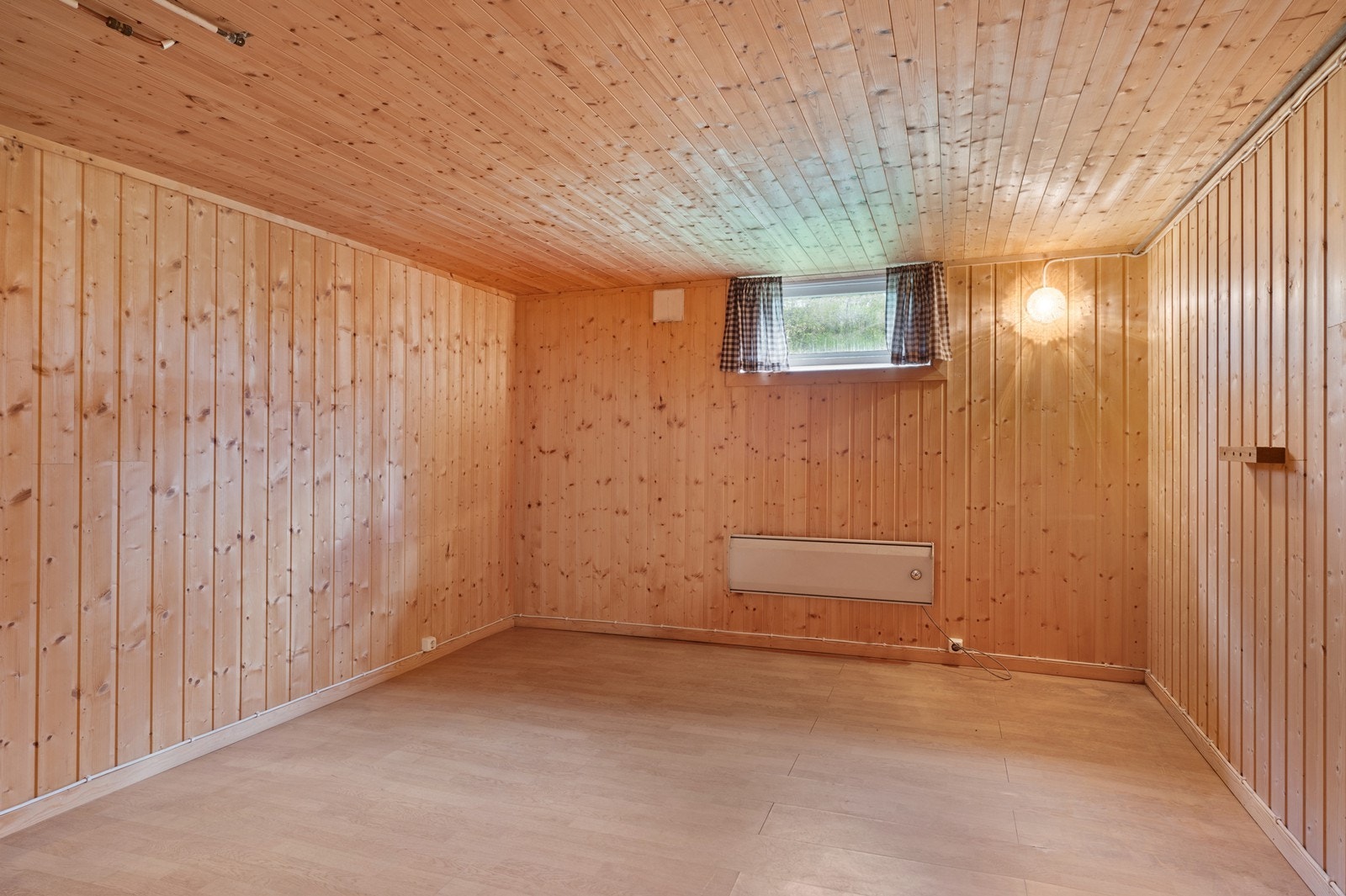 Et annet innredet rom i kjelleren, med panel på vegger og himling. Galleribilde
