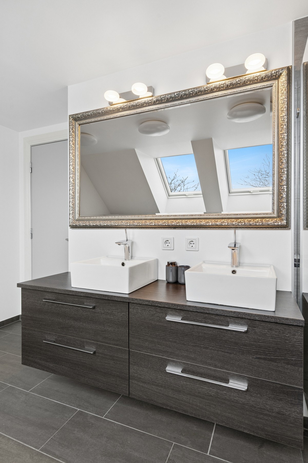 Badet har doble, toppmonterte servanter og flislagt gulv med termostatstyrte varmekabler. Galleribilde