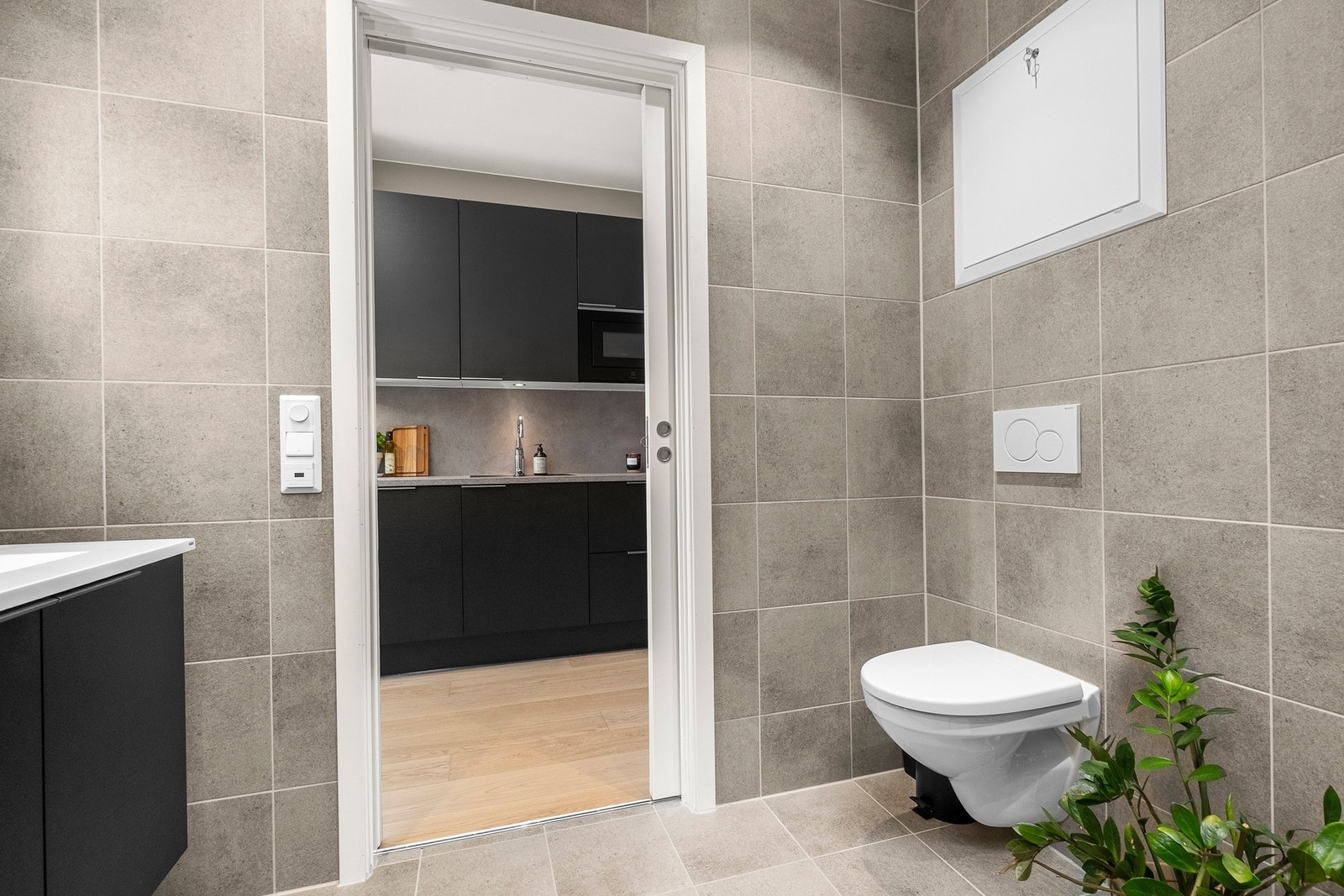 Badet er innredet med vegghengt toalett, servantinnredning og speil med integrert belysning og dusjhjørne med innfellbare glassdører. Galleribilde
