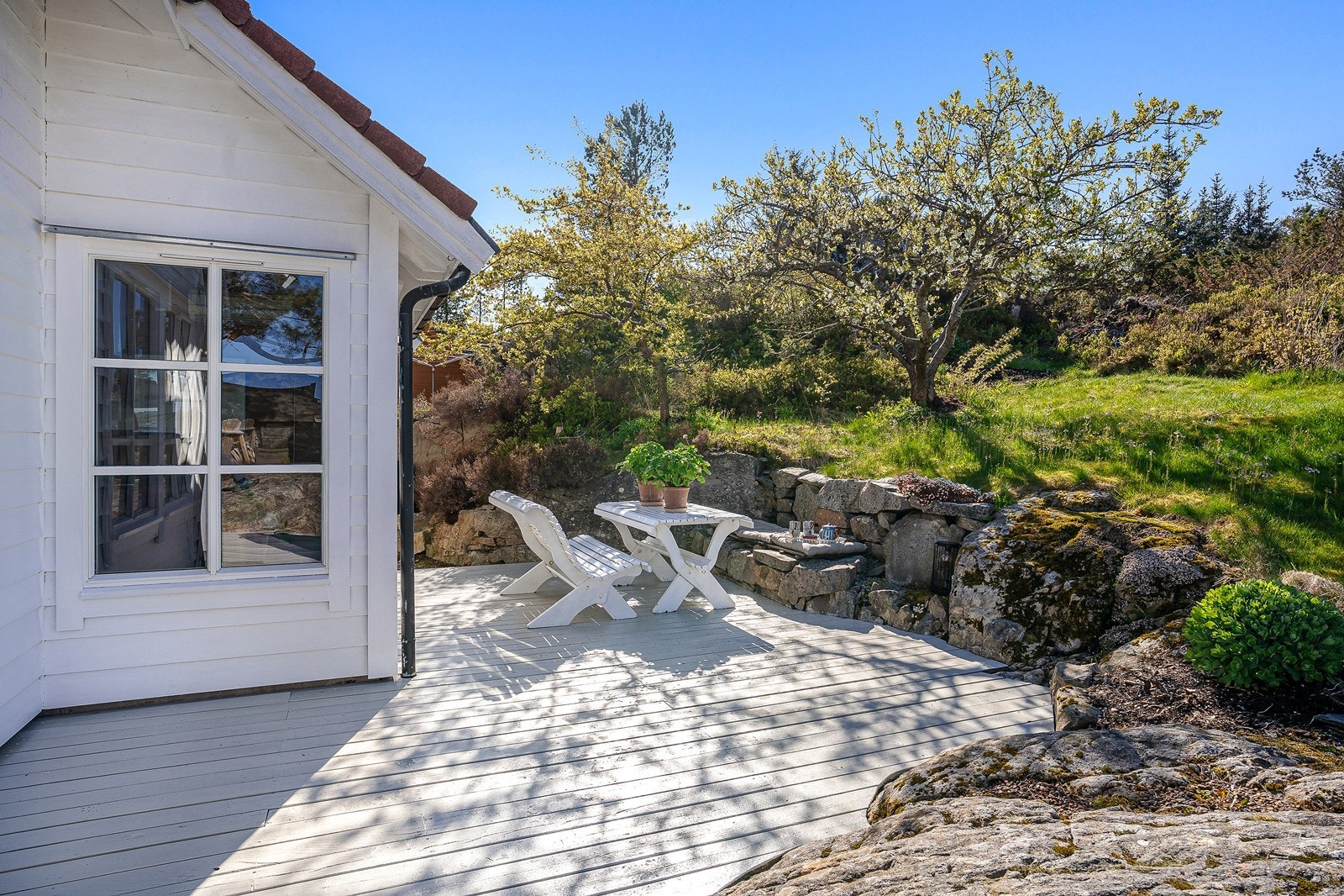 Tomten er pent opparbeidet med natursteinsmurer, hellelagt uteområde, asfalt, plen og flere fine treplattinger. Galleribilde