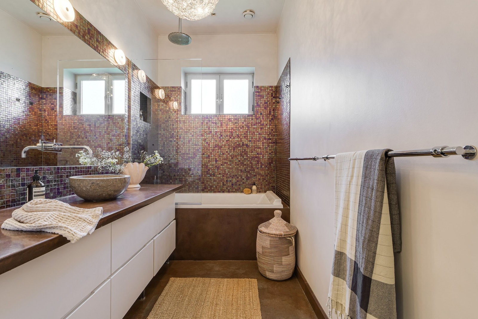 Romslig og særegent baderom med moderne uttrykk og gjennomførte materialvalg. Badet har flislagt gulv med varmekabler. Badet har naturlig oppdriftsventilasjon og tilluft via luftespalte under dør. Galleribilde