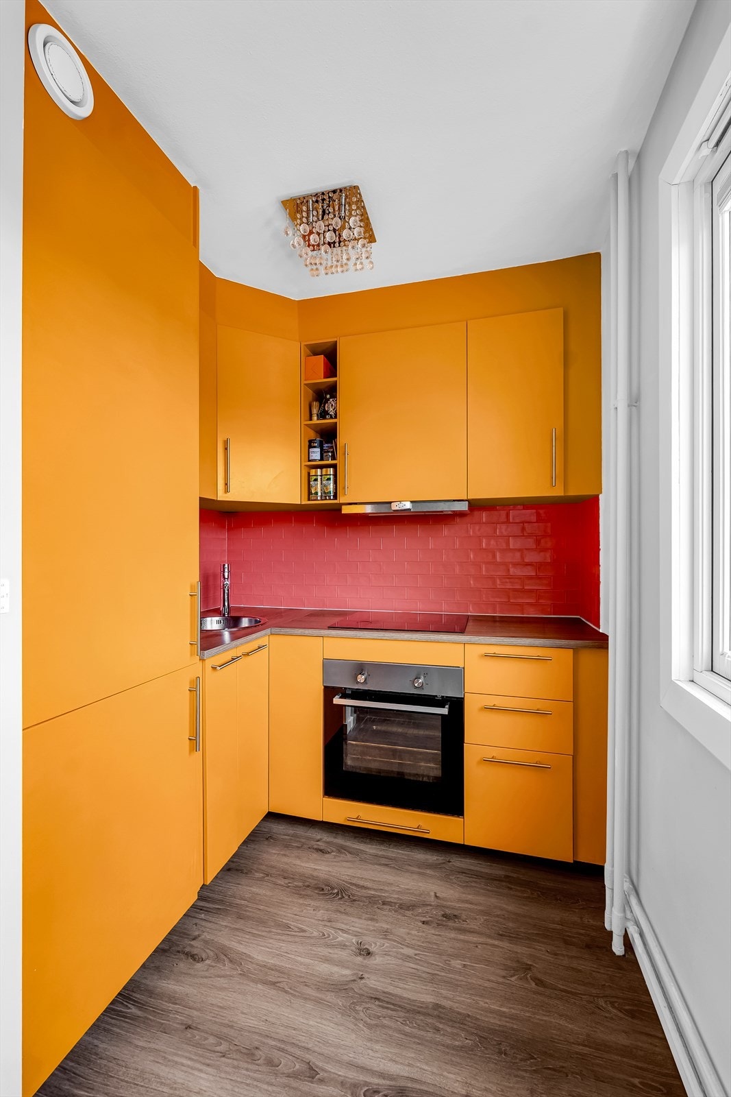 Stilrent kjøkken med innredning bestående av glatte fronter og laminat benkeplate. Integrerte hvitevarer bestående av kjøl/fryseskap, oppvaskmaskin, induksjonstopp og stekeovn Galleribilde
