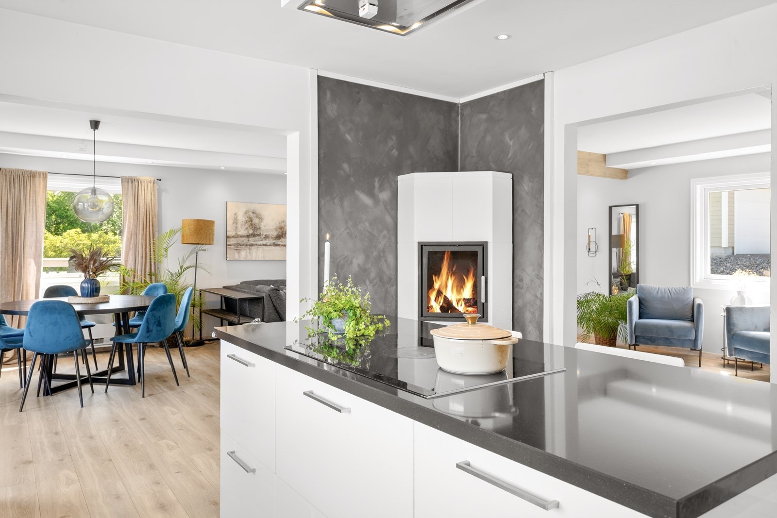 På kjøkkenet har man også en stilren peis med innsats som gir både varme og en lun atmosfære. Peisen er plassert mot en dekorativ vegg med moderne, sementaktig finish som gir rommet karakter. Integrert spotbelysning i himling. Galleribilde