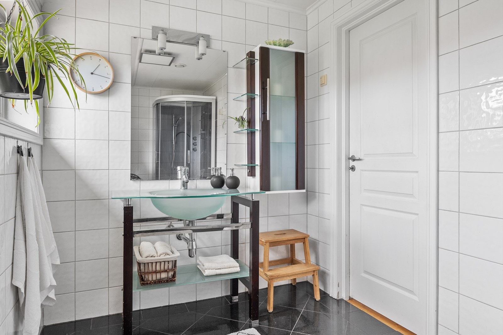Badet inneholder innredning med servant i glass, vegghengt speil, gulvmontert toalett og dusjkabinett. Galleribilde
