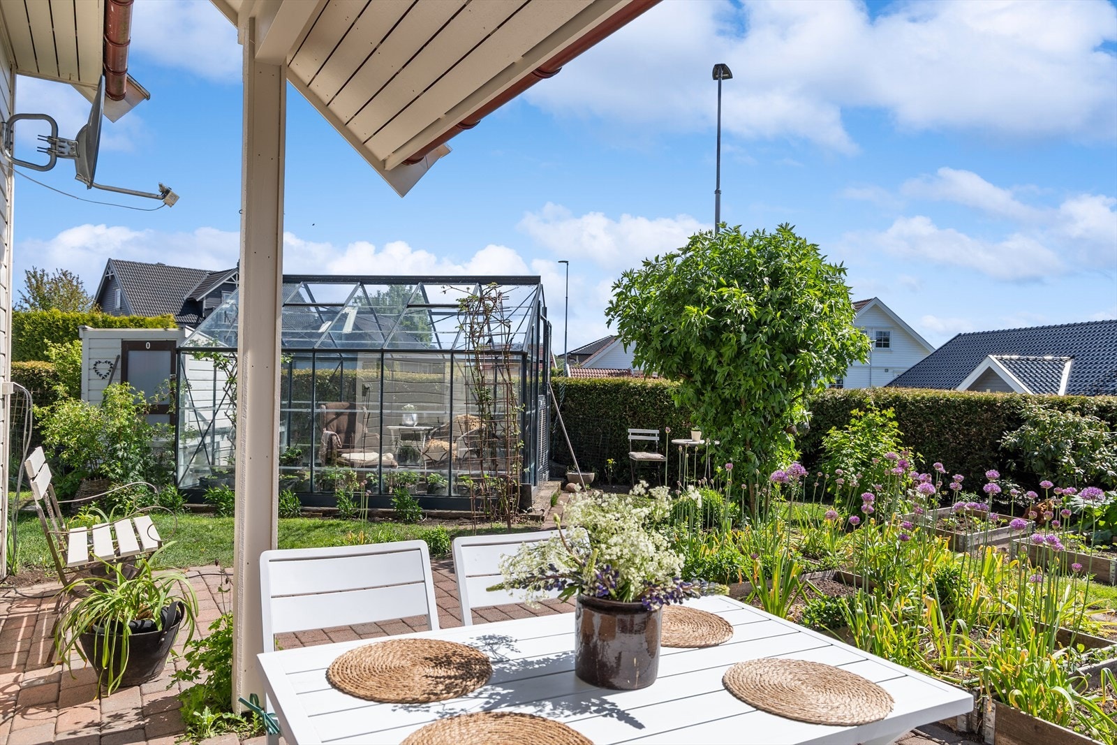 Nåværende eier har utnyttet tomten på imponerende vis, med blomster, nyttevekster, matdyrking og lune soner som gjør uteområdet både praktisk og stemningsfullt. Galleribilde