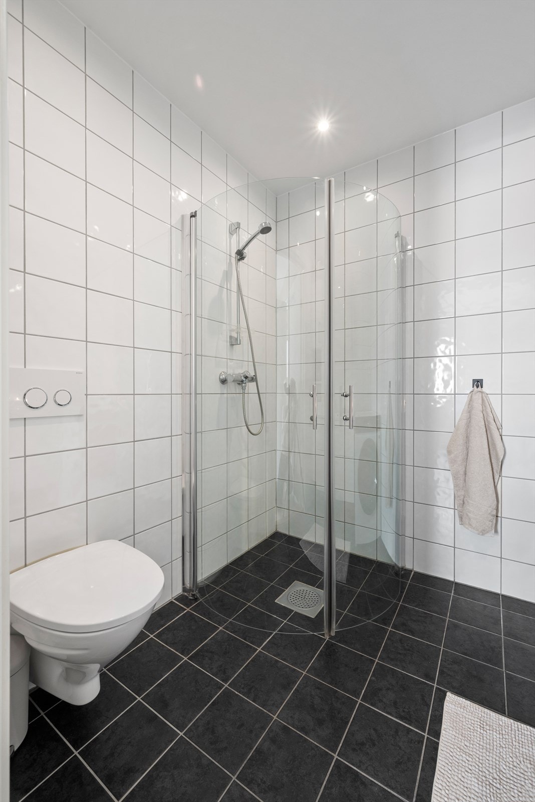 Badet oppe har også gulvvarme og er utstyrt med innfellbare dusjdører, servantskap, veggmontert WC, opplegg for vaskemaskin og mekanisk avtrekk. Galleribilde