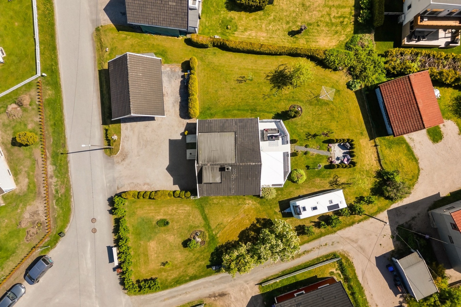 Tomten er opparbeidet med gruset gårdsplass, hage med plen og beplantning. Galleribilde