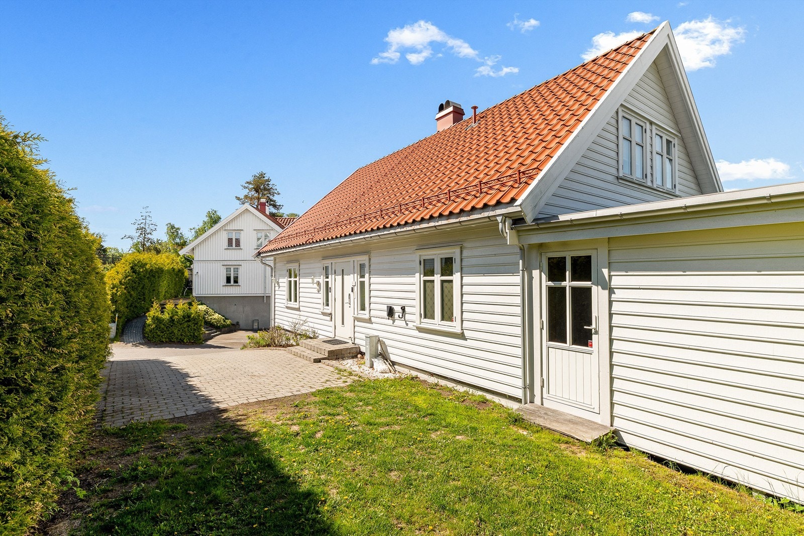 Eiendommen ligger på en skrånende tomt som er opparbeidet med plen og beplantning. Dør til høyre er inn til utestuen. Galleribilde