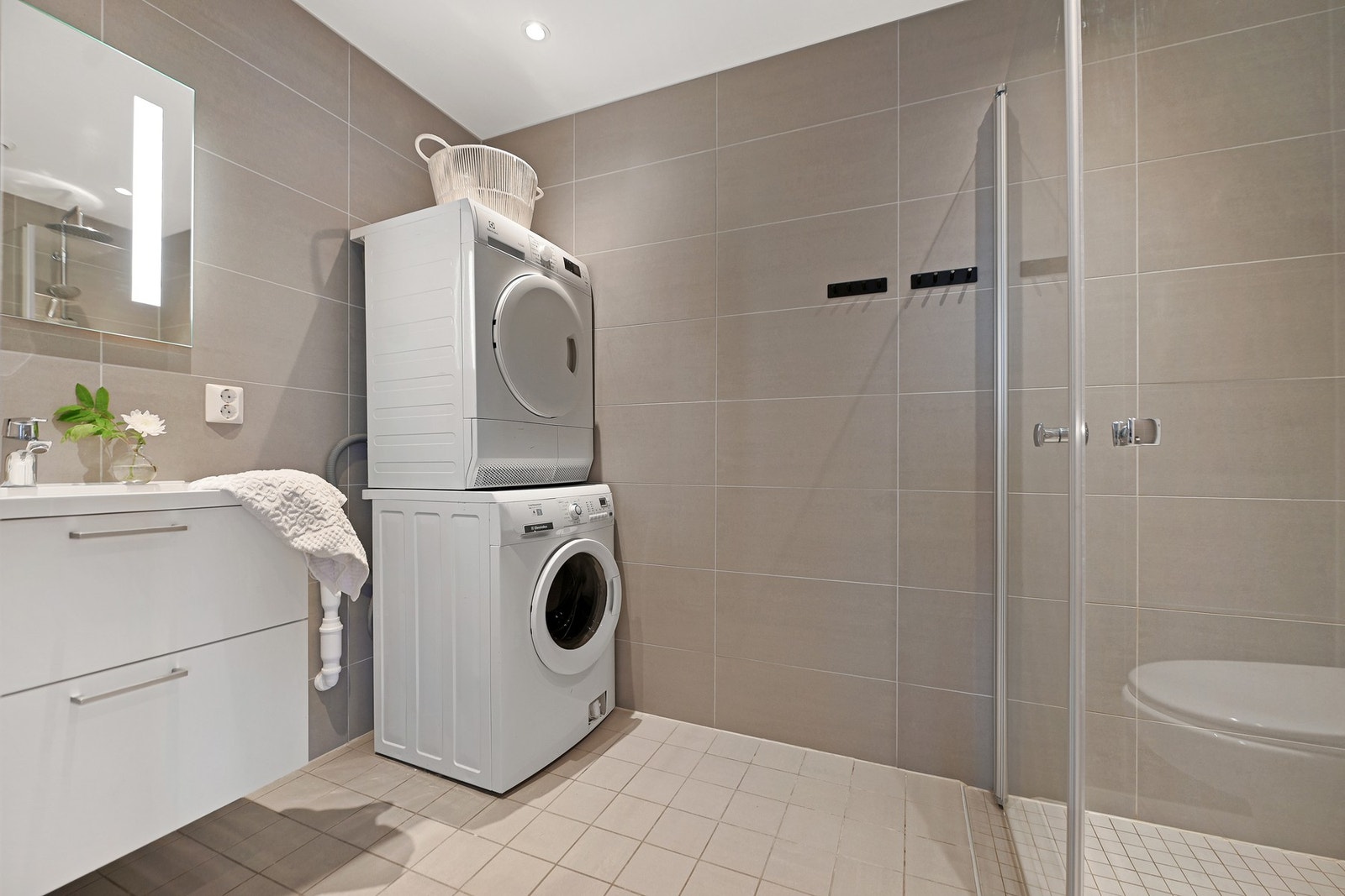 Badet er innredet med servantskap, speil med lys, vegghengt wc, dusjhjørne med takdusj og hånddusj, samt opplegg for vaskemaskin/tørketrommel. Galleribilde