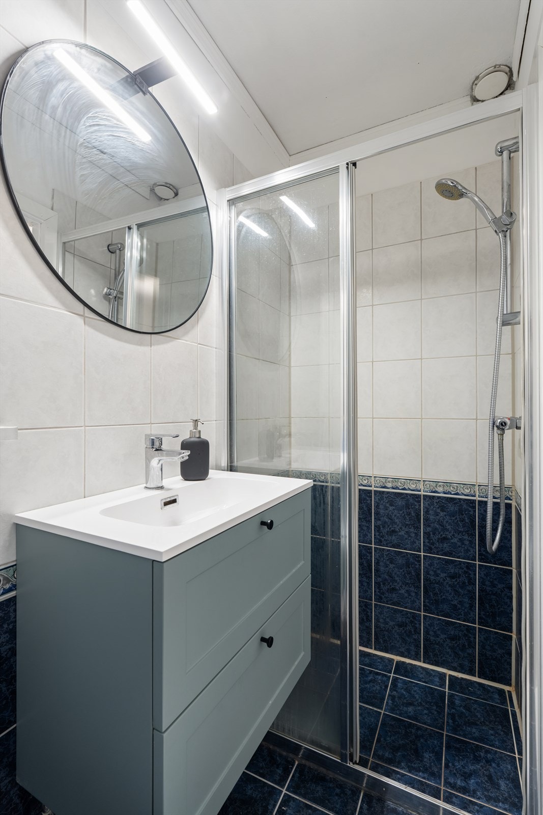 Badet er utstyrt med dusjnisje, servant med underskap, speil med belysning over og toalett. Galleribilde