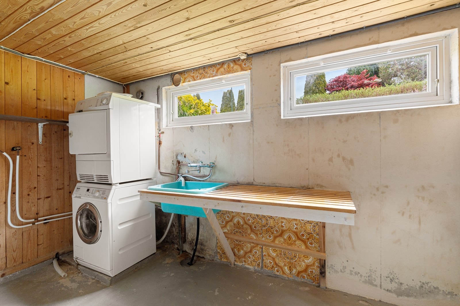 Praktisk vaskerom i kjeller med betonggulv, utslagsvask og opplegg for vaskemaskin. Galleribilde