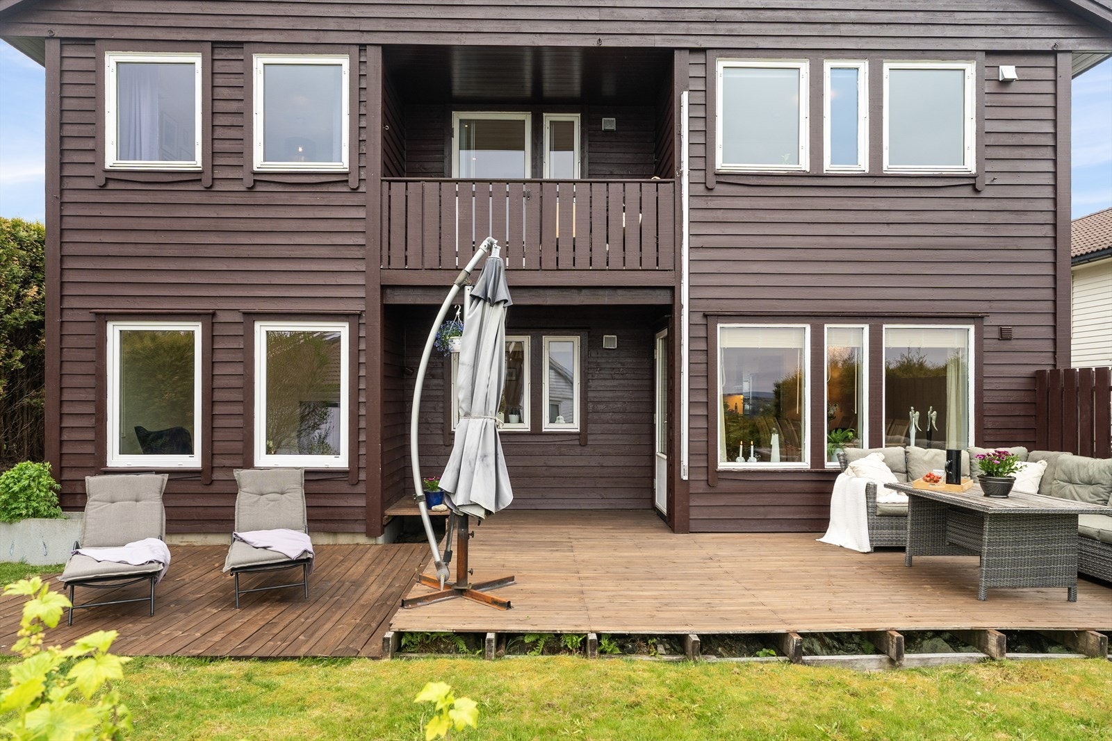 Utgang fra stuen til skjermet, sørvendt uteområde med terrasse og gressplen. Hagen har rips- og solbærbusker. Galleribilde