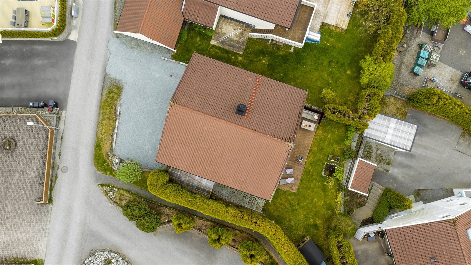 Flyfoto som viser eiendommens fine opparbeidede uteområder med romslig gårdsplass og koselig uteplass. Galleribilde