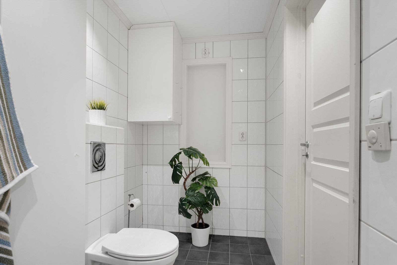 Badet har vegghengt toalett, dusjkabinett, vask, skap og skittentøyssjakt. Galleribilde