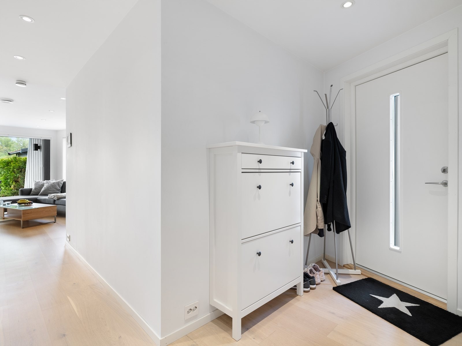 Inngangspartiet ønsker velkommen med en ny dør fra 2023 og leder direkte inn i leilighetens åpne oppholdsrom. Galleribilde