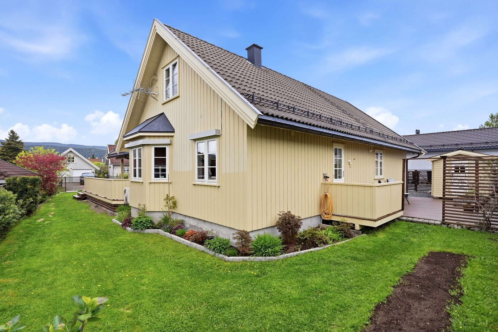 Eiendommen har en velstelt hage med plen, bed og beplantning. Galleribilde