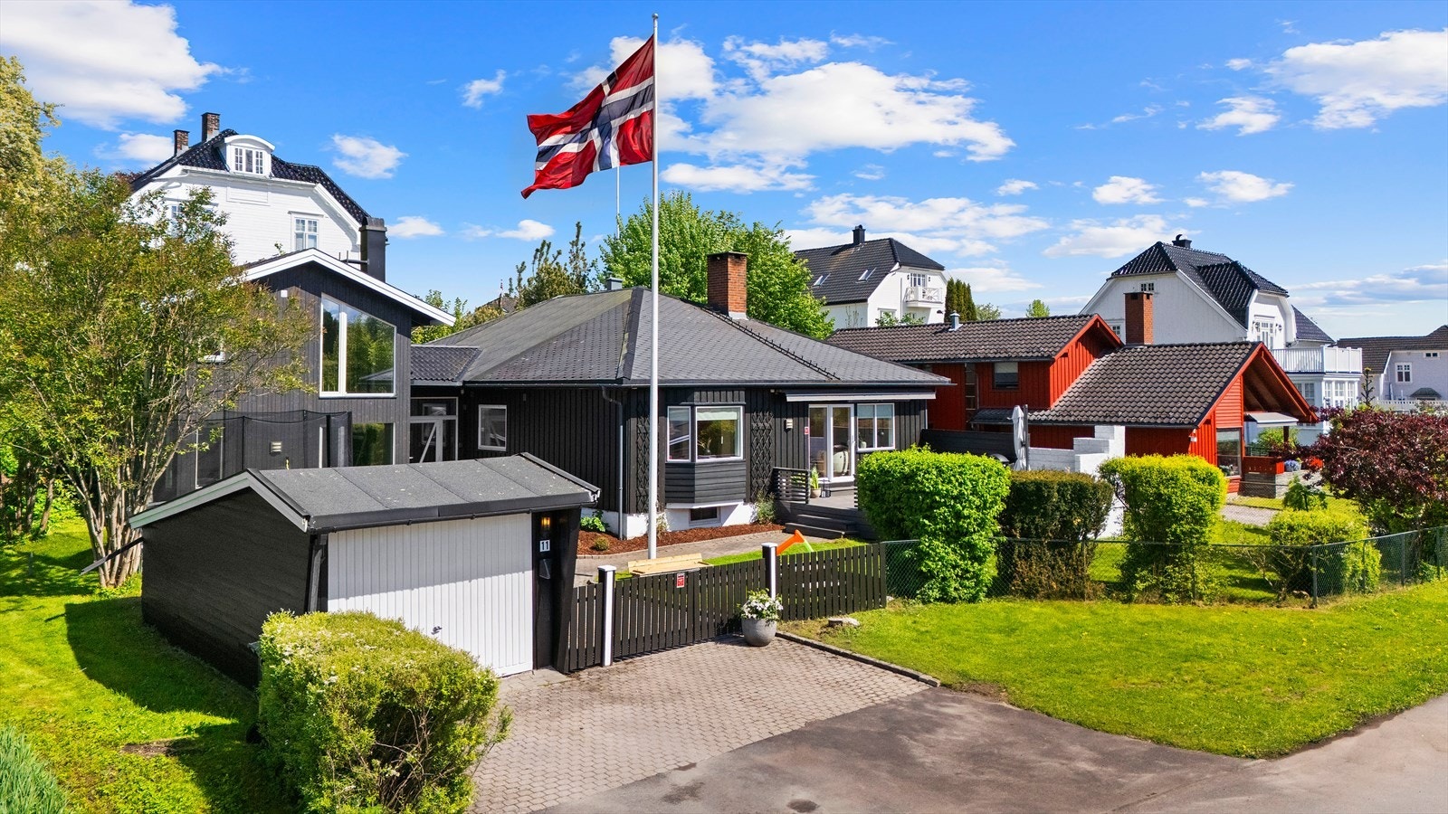 Tomten er pent opparbeidet med belegningsstein og plen, samt rikt beplantet med et variert utvalg av prydbusker, prydtrær og blomsterbed Galleribilde