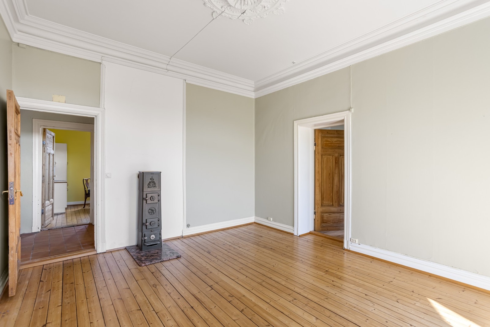 Romslig og lys stue med klassiske detaljer som stukkatur og rosett, kombinert med store vindusflater som slipper inn rikelig med naturlig lys. Galleribilde