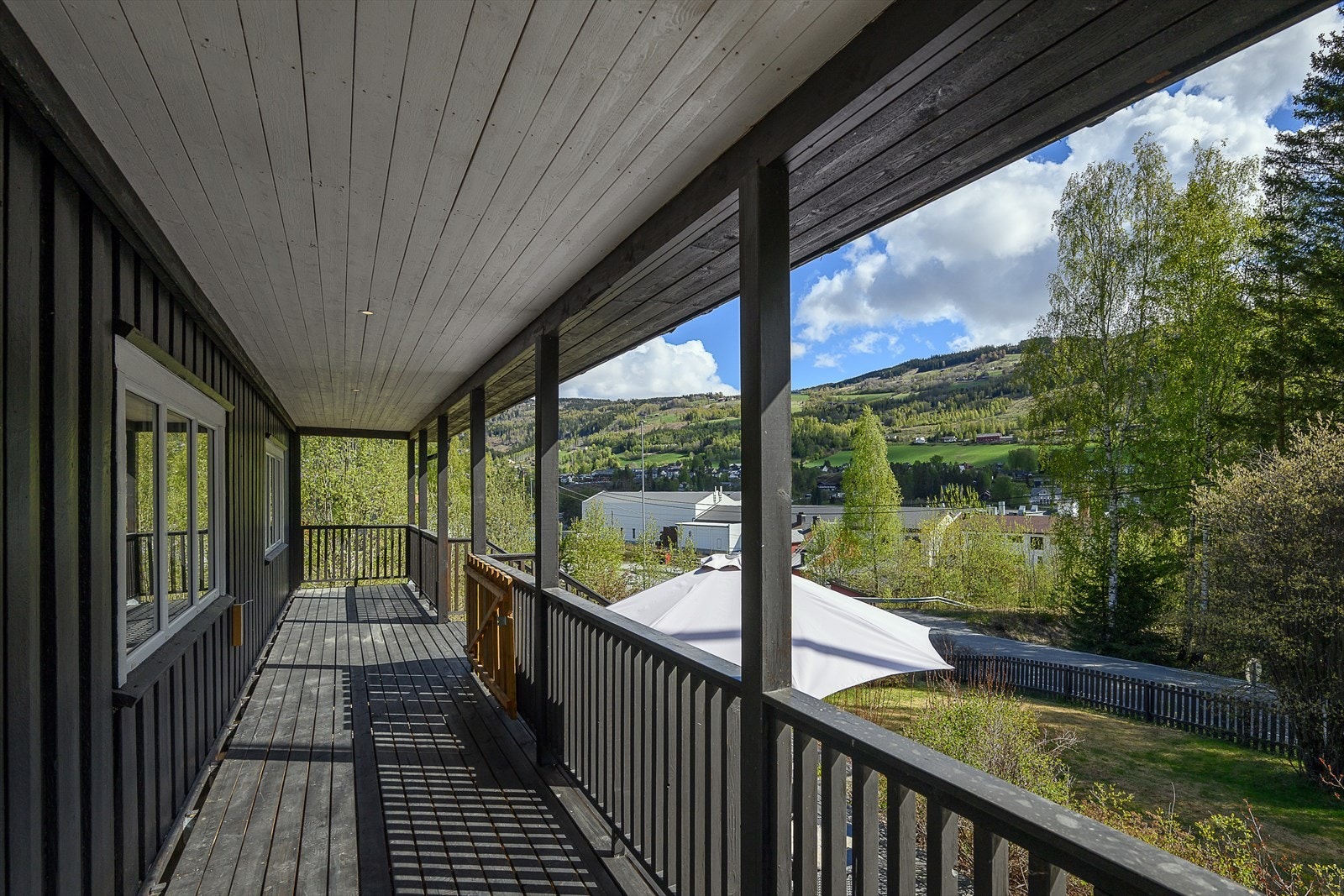Den østvendte, takoverbygde verandaen har trapp ned til en platting på bakkeplan. Galleribilde