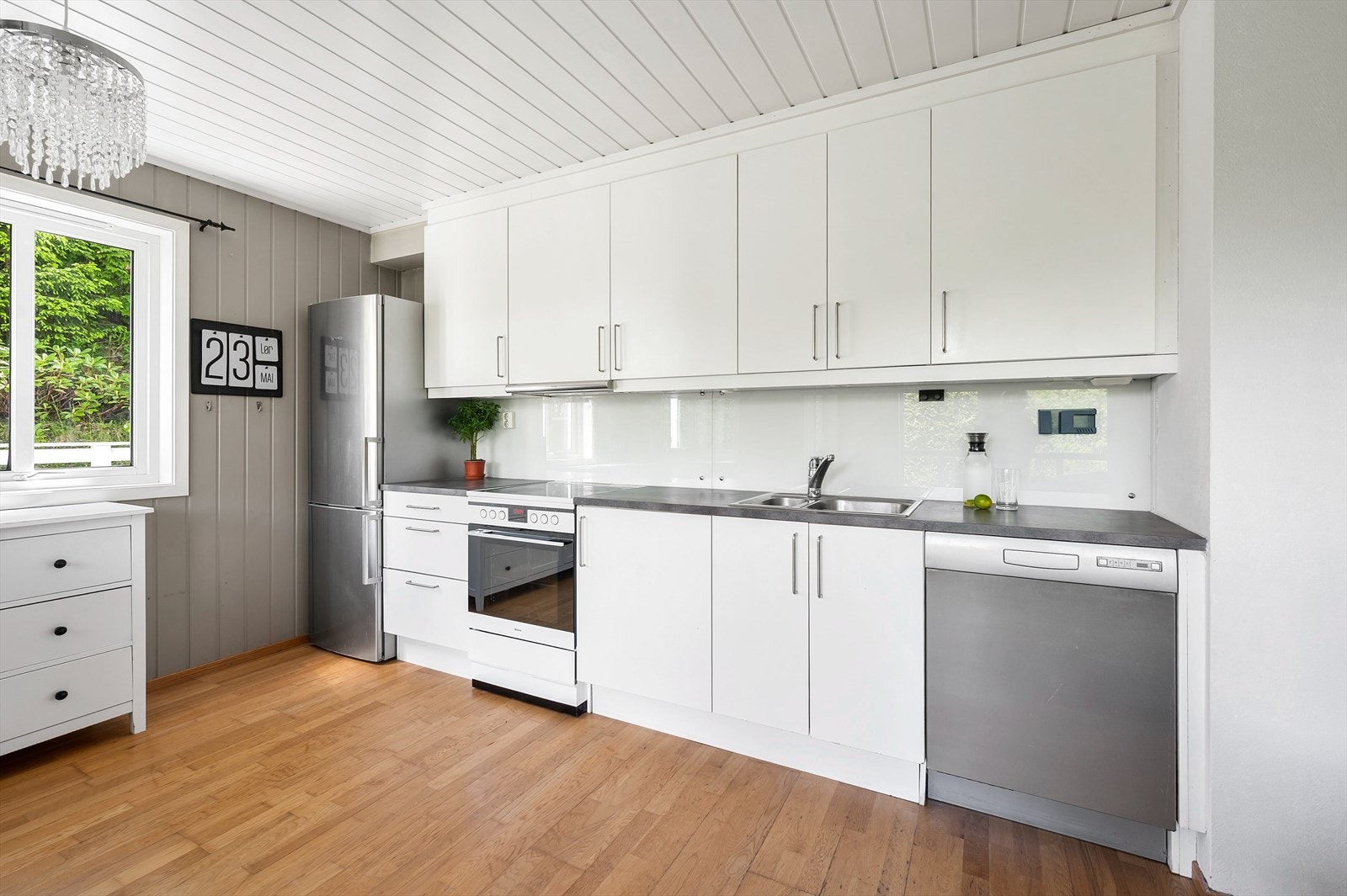 Kjøkkeninnredning med glatte fronter, benkeplate i laminat og ventilator med avtrekk ut. Galleribilde