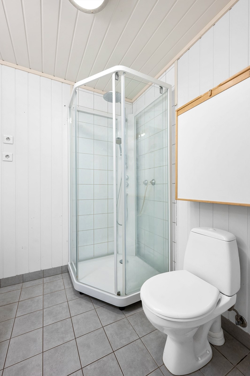 Badet er utstyrt med dusjkabinett, toalett og elektrisk styrt avtrekksvifte. Galleribilde