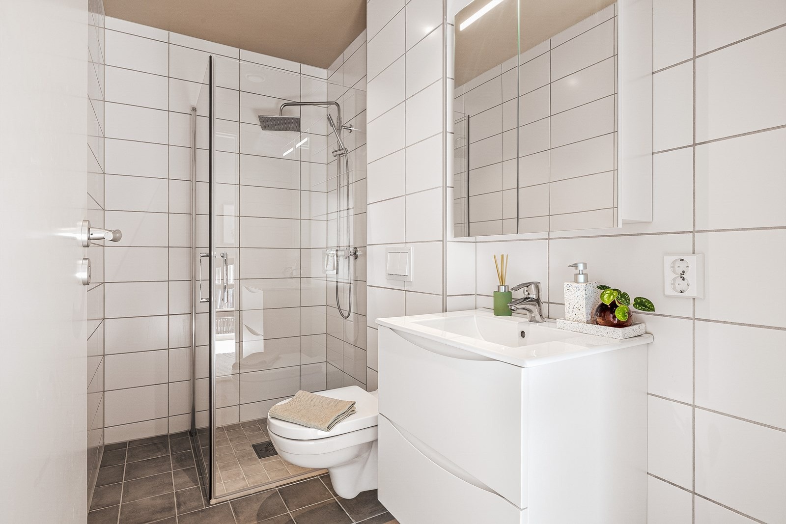 Klassisk og helfliset bad med varme i gulv. Badet er innredet med nedfelt servant med møblement, veggmontert toalett, dusjhjørne, og balansert ventilasjon. Galleribilde