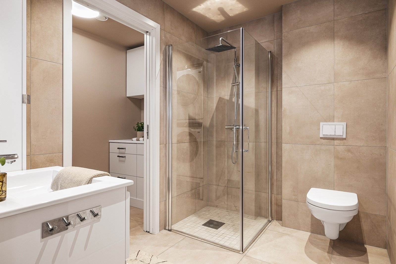 Badet er innredet med nedfelt servant med møblement, veggmontert toalett, og et dusjhjørne. Galleribilde