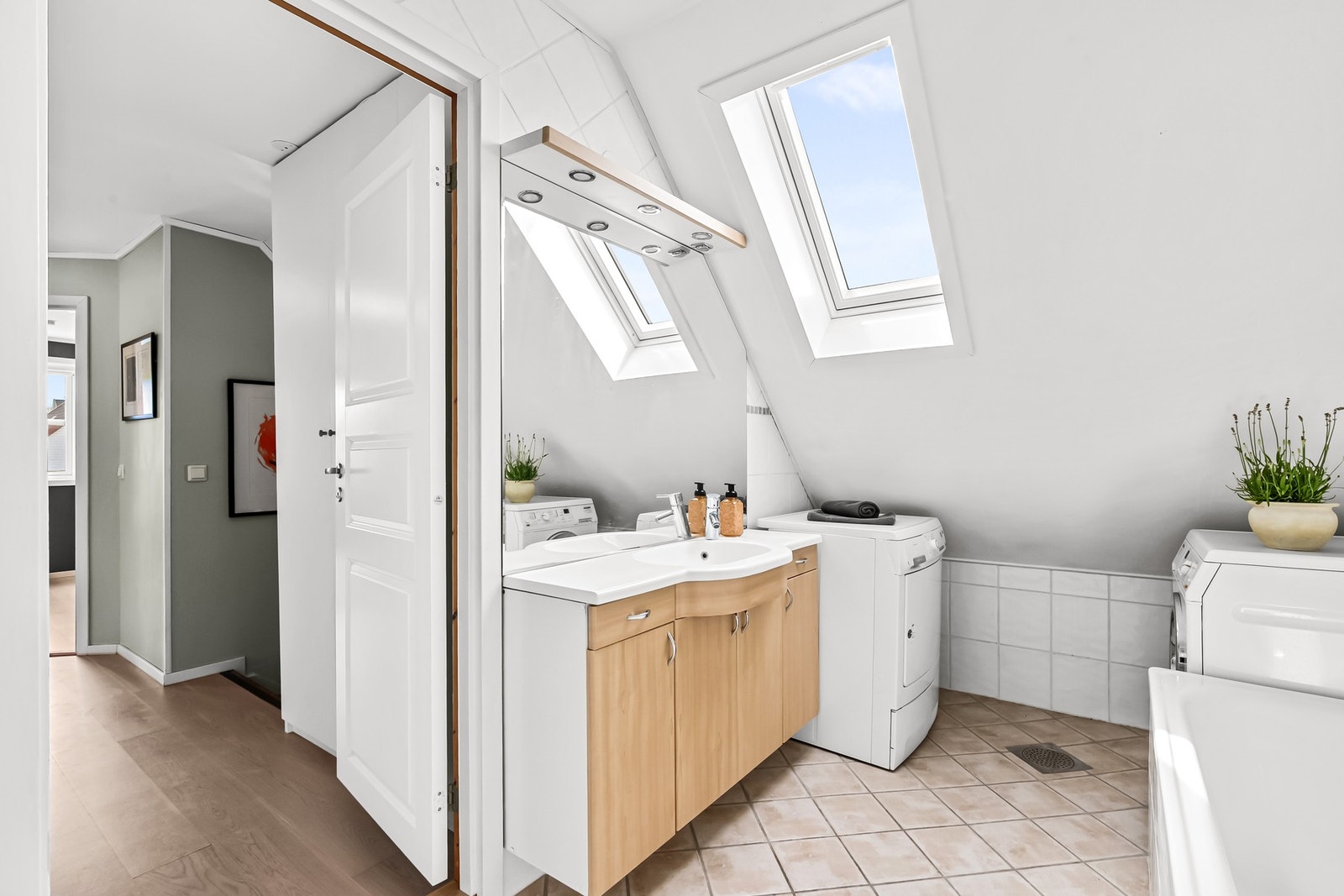 Videre er det servantskap med glatte fronter, heldekkende servant og speil med lysarmatur over servant. Det er opplegg for vaskemaskin og tørketrommel. Galleribilde
