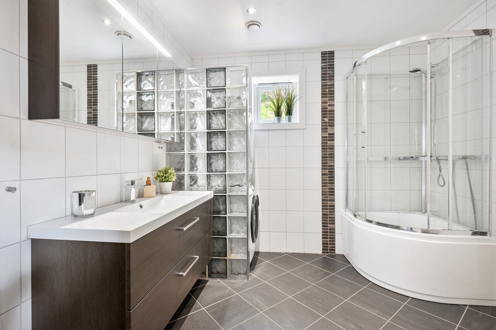 Badet i 1. etasje fremstår som romslig og moderne med flislagte overflater og en funksjonell planløsning. Galleribilde