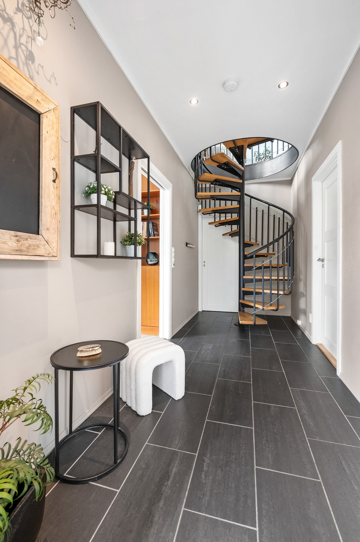 Entré og gang fremstår som moderne og innbydende med den elegante vindeltrappen i stål og tre fungerer som et naturlig blikkfang og tilfører boligen et eksklusivt og moderne preg. Galleribilde