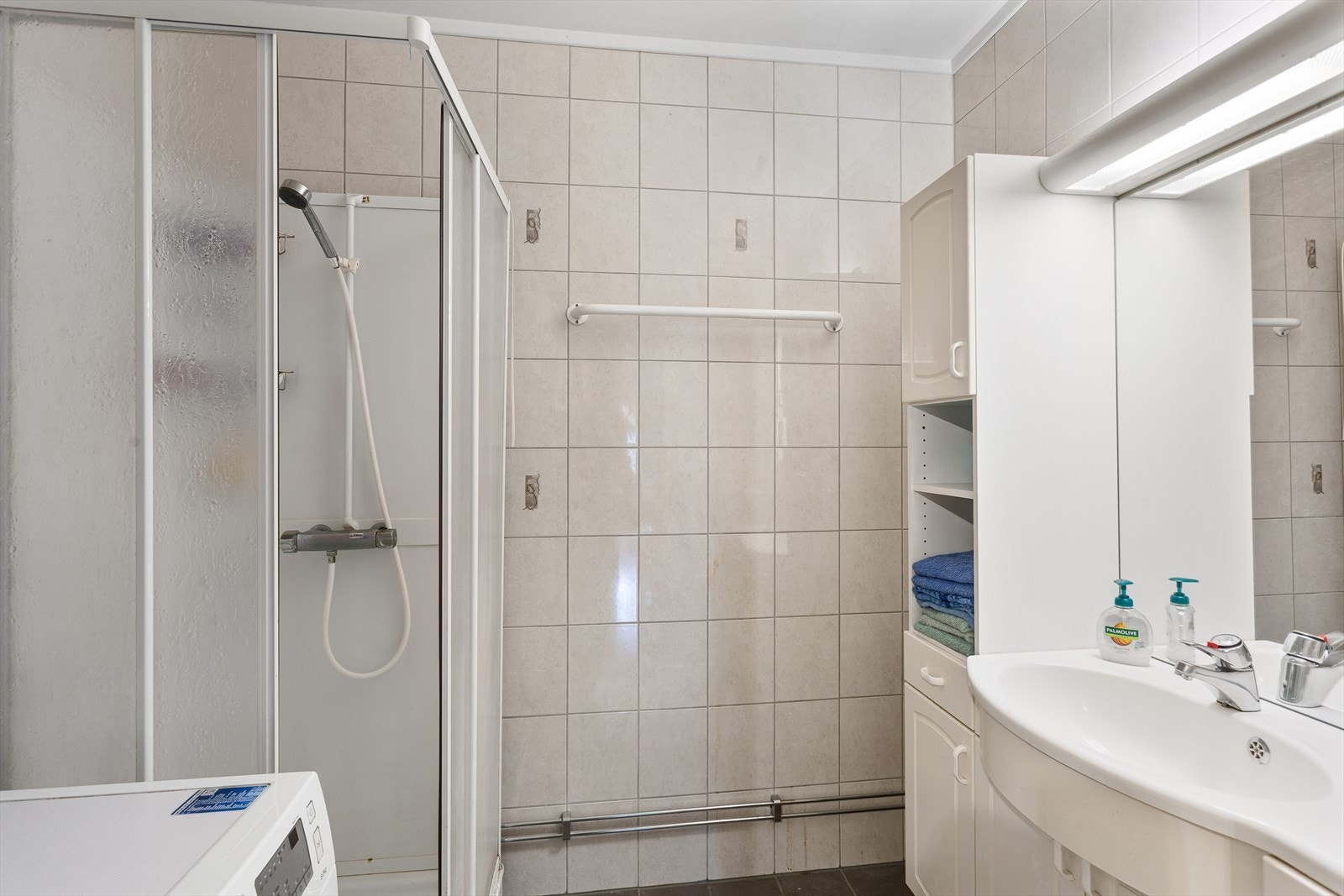 Lyst bad med fliser på gulv og vegger og rikelig med oppbevaringsmuligheter! Galleribilde