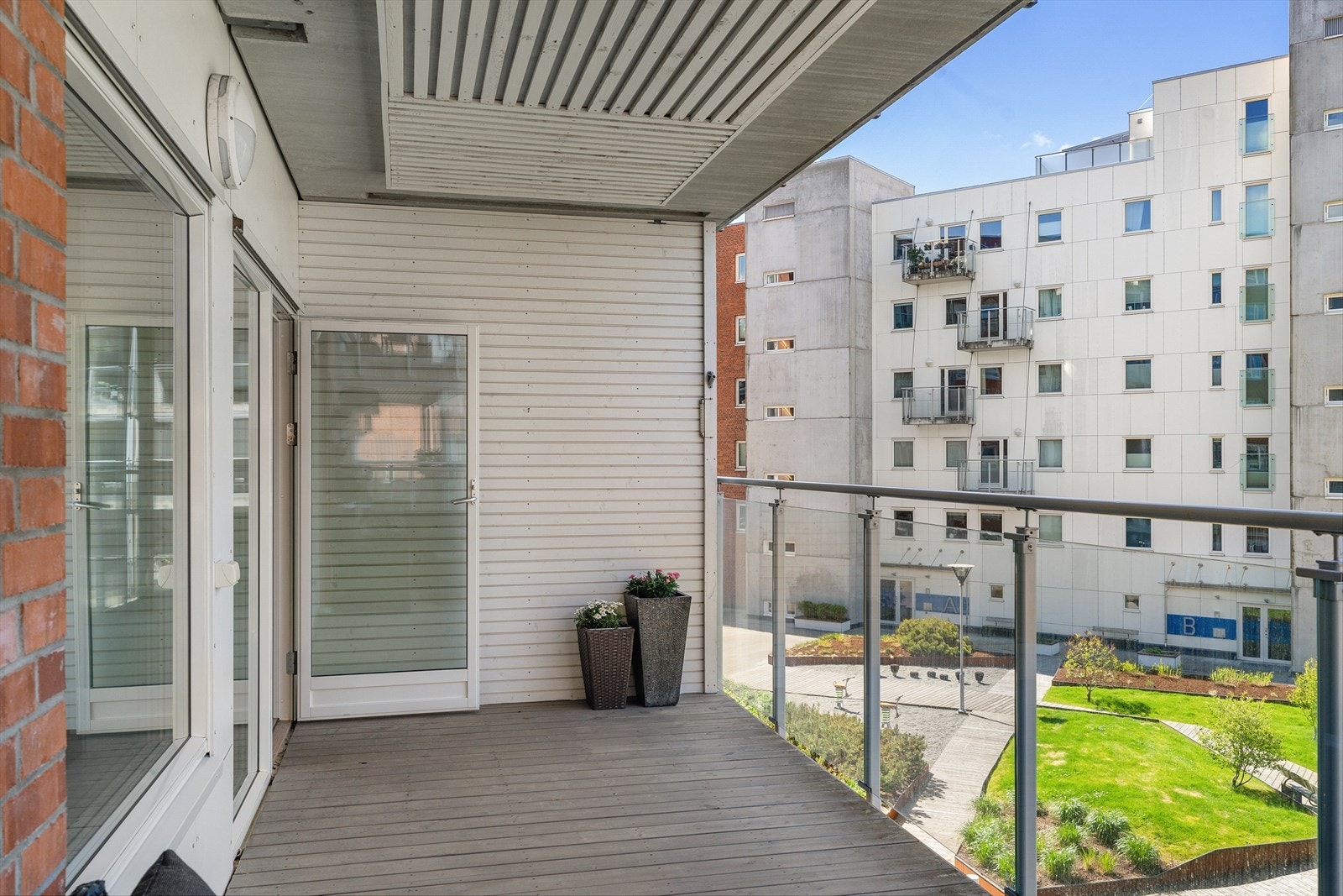 Utgang fra stue til en stor balkong på ca. 15 m² med rekkverk i glass. Galleribilde