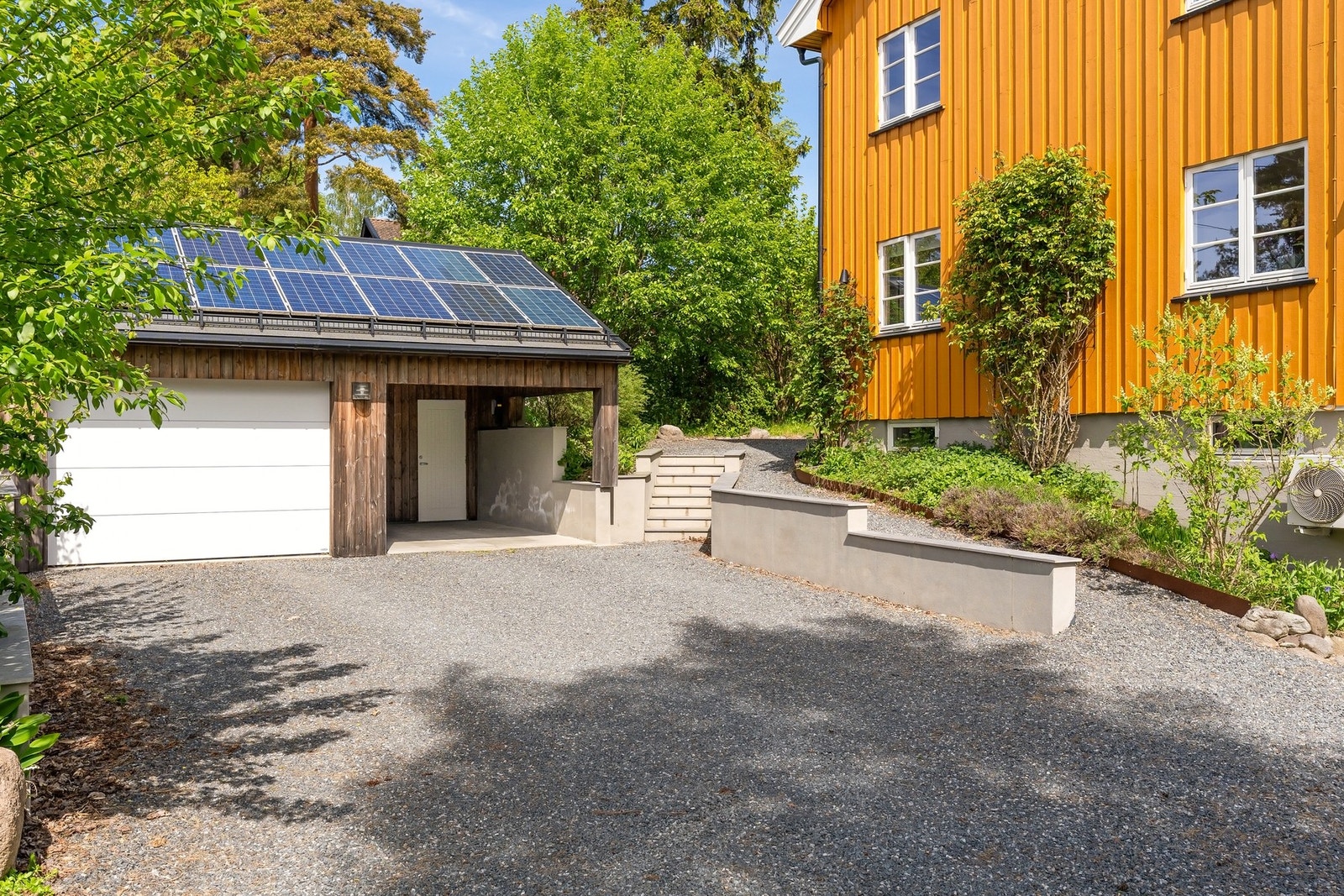 Gruslagt gårdsplass. Boligen har en frittstående garasje med carport samt en integrert garasje Galleribilde