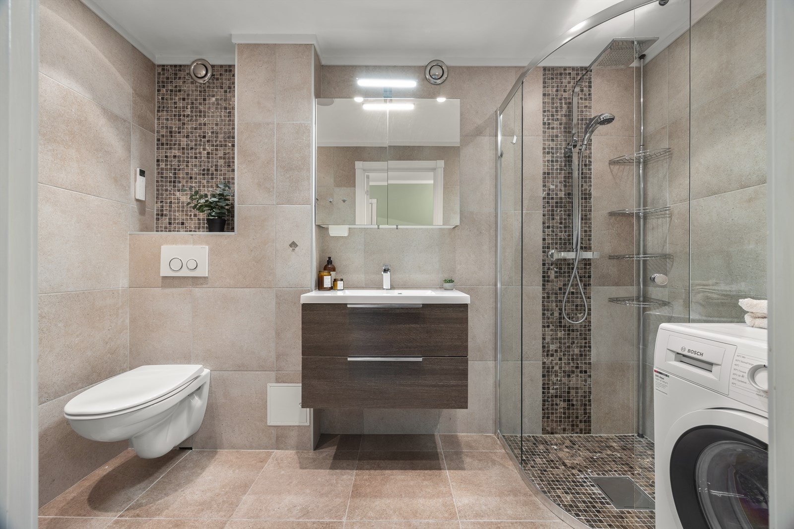 Delikat flislagt baderom (2014) med varmekabler i gulv og downlights i himling. Badet inneholder bl. a. et praktisk speilskap, veggskap og vegghengt klosett. Galleribilde