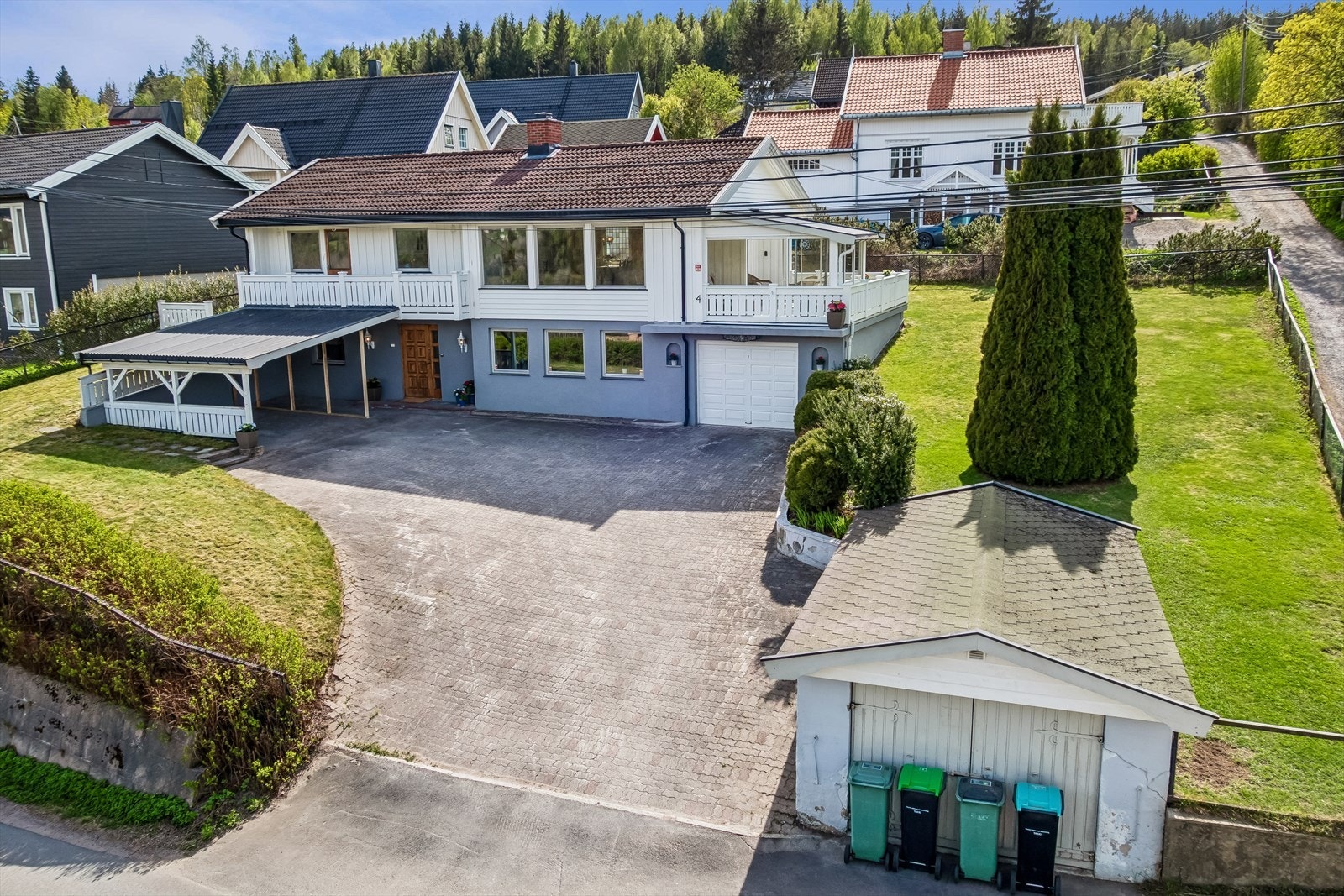 Eiendommen har en stor, belegningssteindekket gårdsplass med carport, frittstående garasje og integrert garasje. Galleribilde