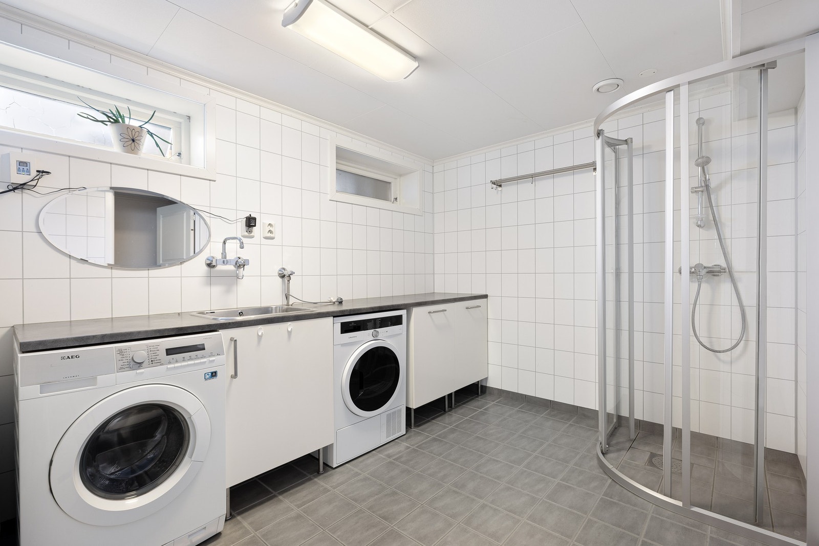 Praktisk vaskerom med dusjhjørne, toalett, utslagsvask og opplegg for vaskemaskin og tørketrommel på vegg. (Opprinnelig godkjent som bod). Galleribilde