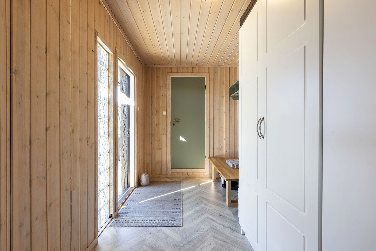 Praktisk og innbydende entré med laminatgulv og panelte vegger. Her er det god plass til oppbevaring av yttertøy og sko, samt mulighet for garderobeskap. Fra entréen er det inngang til bad på venstre side, mens resten av hytta er videre inn til høyre. Galleribilde