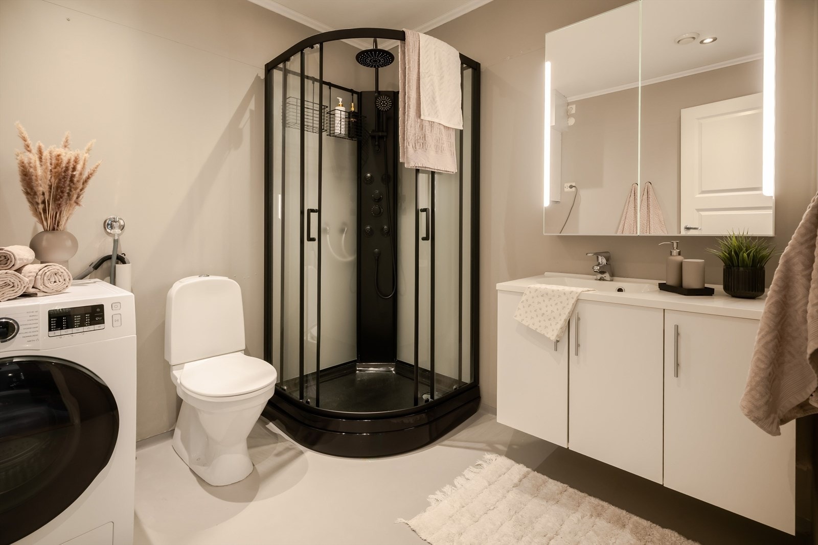 Rommet er utstyrt med dusjkabinett, servantinnredning, wc og opplegg for vaskemaskin. Galleribilde