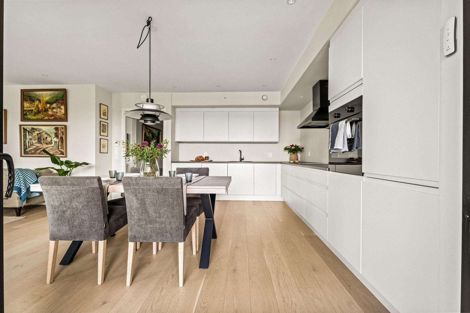 Innredningen har et tidløst uttrykk med hvite, glatte fronter, grå benkeplate av laminat og sort oppvaskkum i kompositt. Galleribilde
